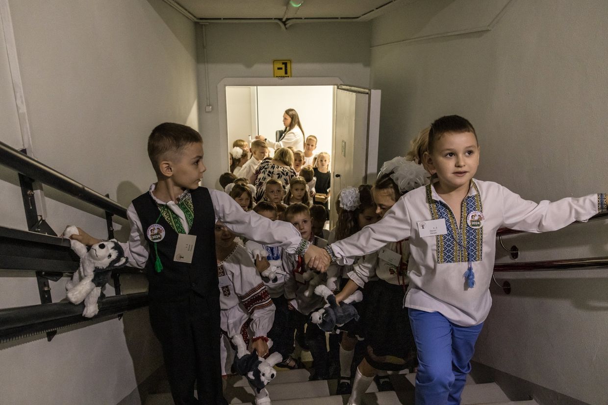 First-grade children walk out from the underground school after the first day of school festivities 